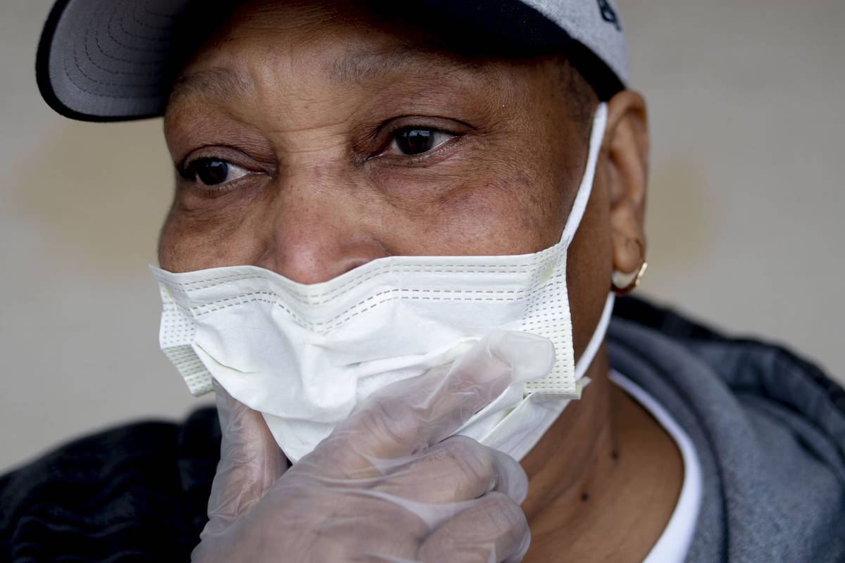 Jacqueline Lee of Flint adjusts her mask in public with gloves on her hands as she tries to pro ...