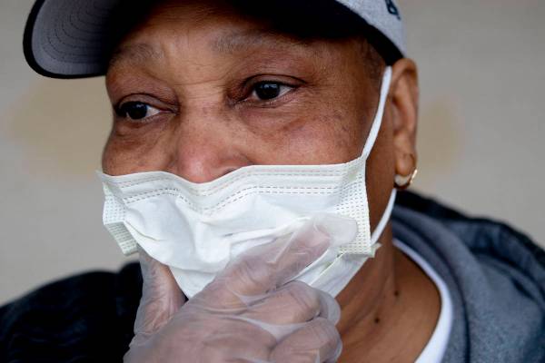 Jacqueline Lee of Flint adjusts her mask in public with gloves on her hands as she tries to pro ...