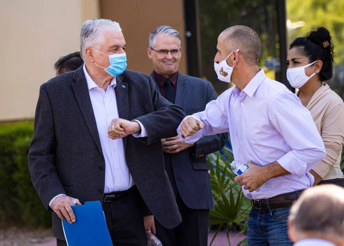 Gov. Steve Sisolak, left, elbow bumps Hans Hippert, owner of Jojo's Jerky, after a press confer ...