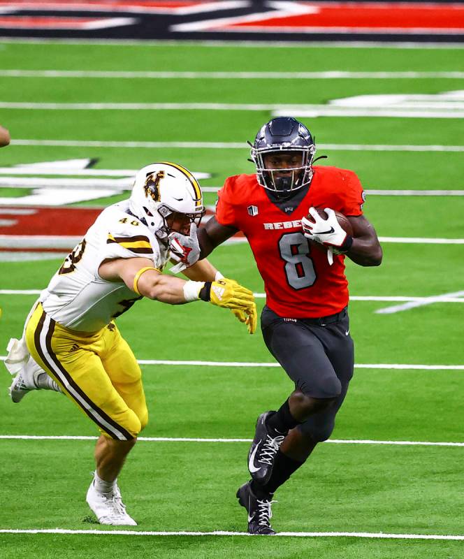 UNLV Rebels running back Charles Williams (8) runs the ball under pressure from Wyoming Cowboys ...