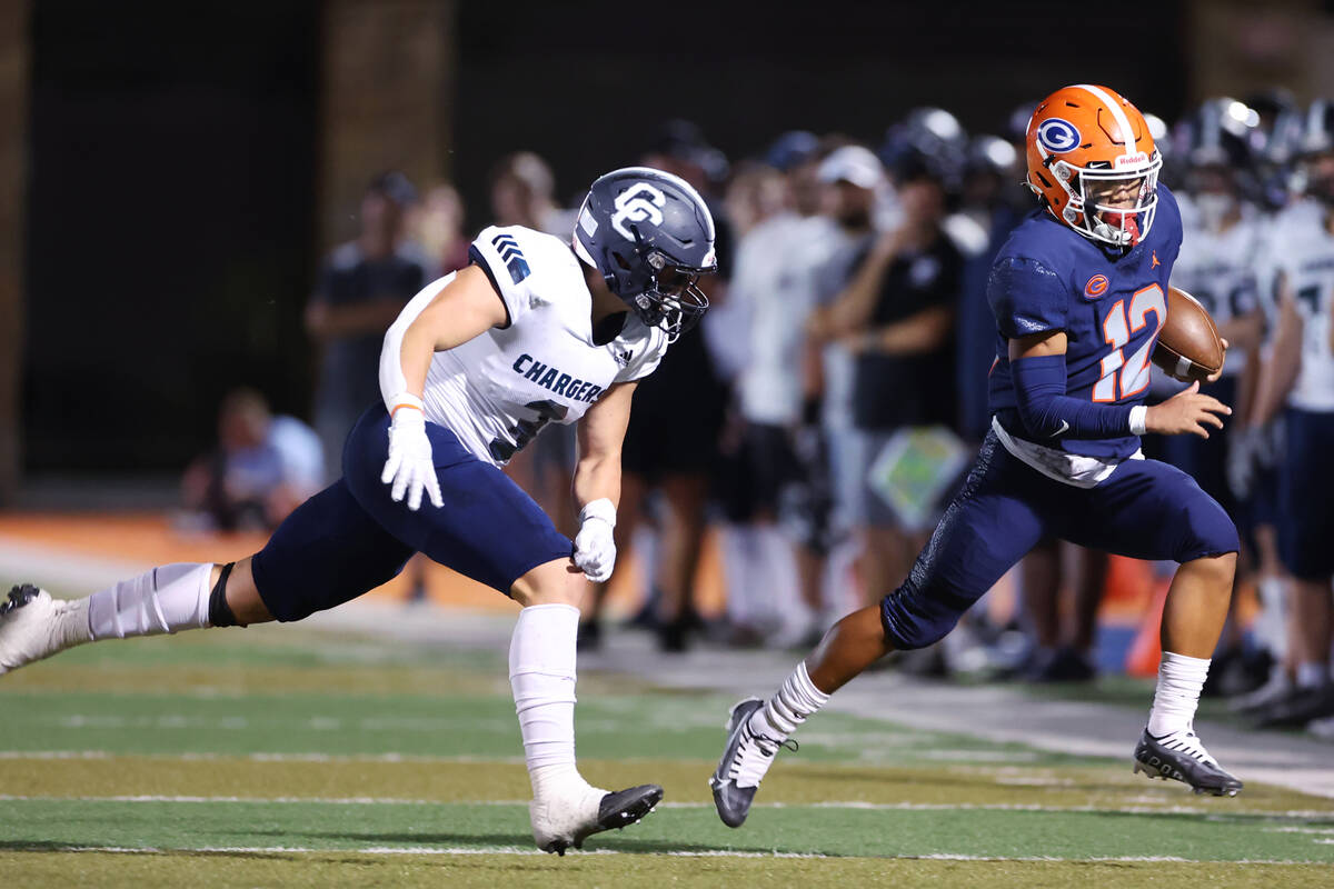 Bishop Gorman's Micah Alejado (12) runs the ball under pressure from Canyon's Dave Brinton (3) ...