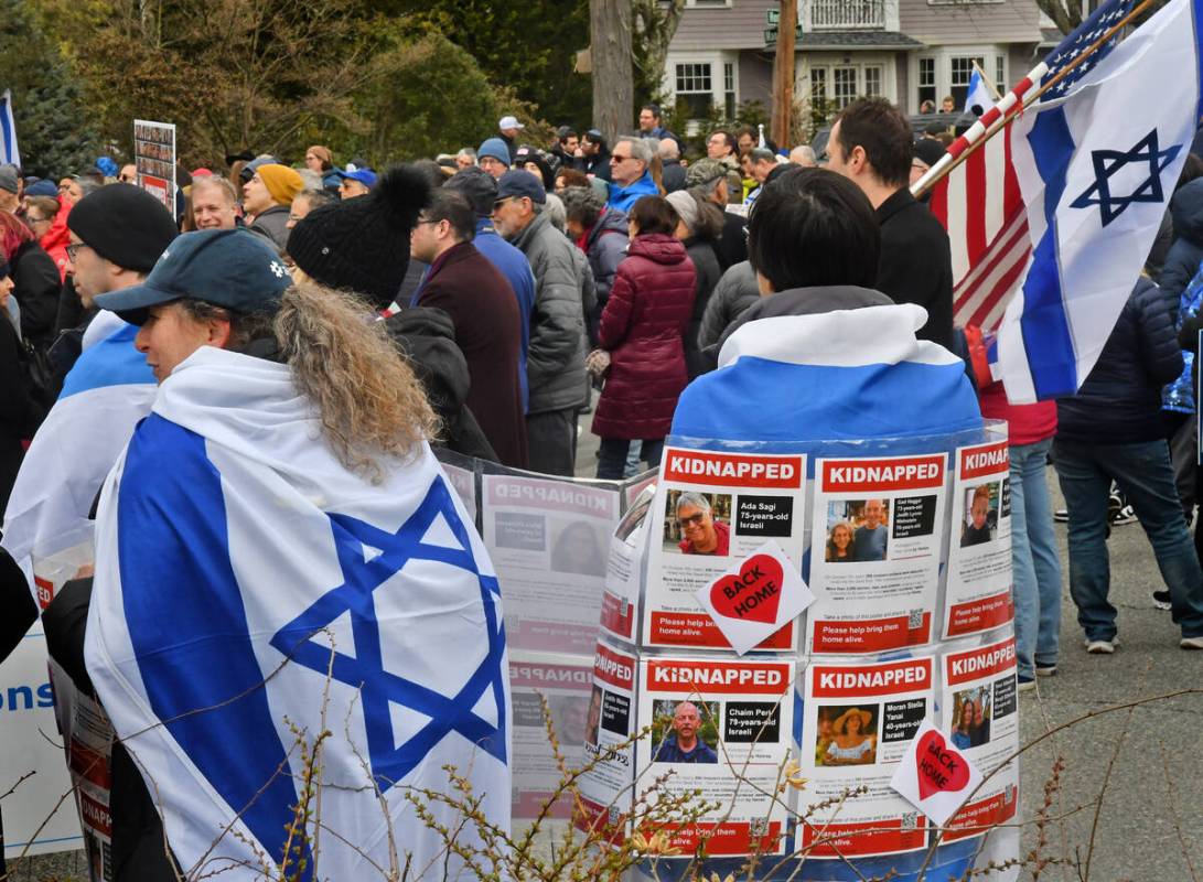 People gather to dedicate the rebuilt vandalized hostage memorial wall in front of a home on Ho ...