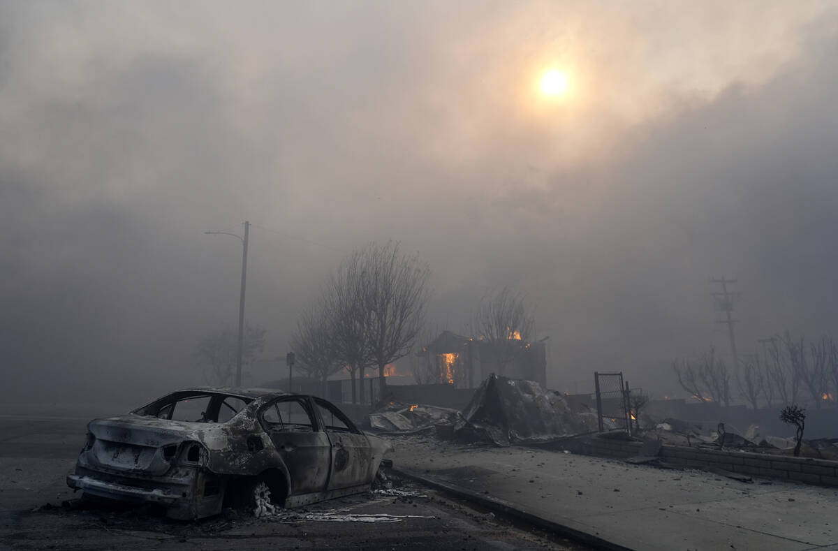 FILE - A burned-out car sits among rubble in the downtown Altadena section of Pasadena, Calif., ...