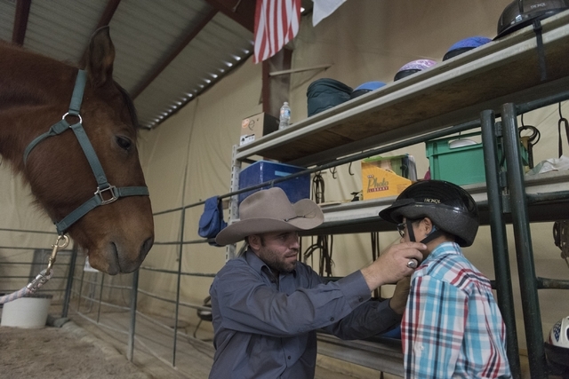 Paul Rogers, co-owner of Paradise Ranch, puts a helmet on eight-year-old Diego Diaz prior to Diaz's horse-assisted therapy session at the ranch at 1722 Primrose Path in Las Vegas Saturday, Feb. 13 ...