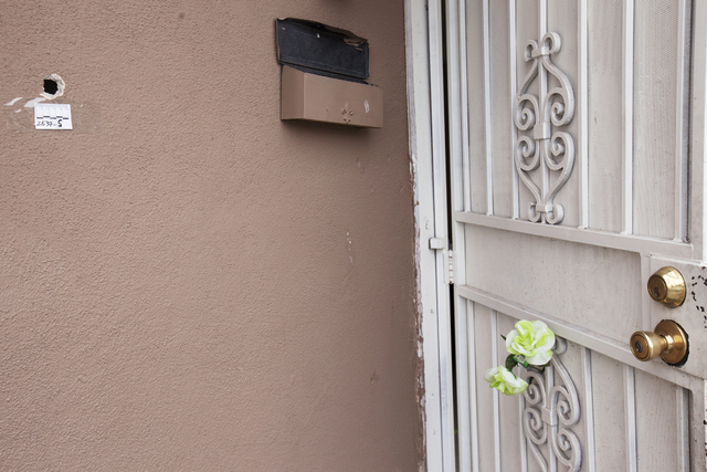 A bullet hole and a fake flower are seen Monday, April 25, in the front of the house at the 2400 block of Page Street where a 24-year-old man was found shot to death early Sunday morning in North  ...