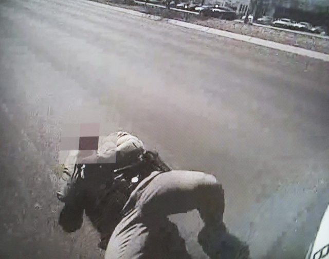 A video screen image shows officer Evan Hogue, 28, grabbing his neck after a bullet fired from suspect James Todora's gun struck him on July 10, 2015, part of evidence presented during a fact-find ...