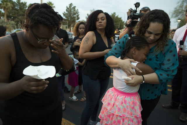 Shanelle Garbutt, far right, embraces her student Lehairah Jackson, who was a classmate of 9-year-old murder-suicide victim Anhurak Dej-Oudom, during a candlelight vigil for the victims of a murde ...