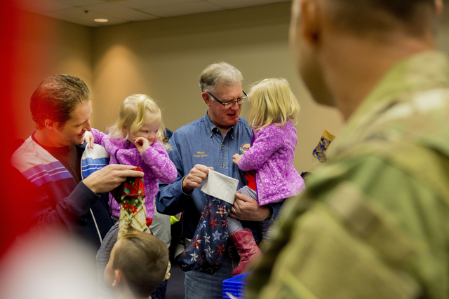Henderson Mayor Andy Hafen, right, holds his granddaughter Aly Hafen, with his son A.K. Hafen, holding his daughter Ava, while they fill stockings for troops serving overseas during the 8th annual ...