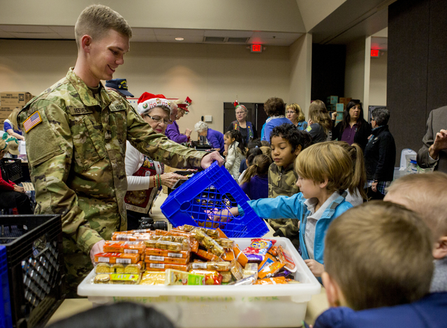 Cody Reeves, of the U.S. Army, volunteers at the food station while students from Gordon McCaw Elementary School fill stockings for active troops overseas during the 8th annual &quot;Stockings ...