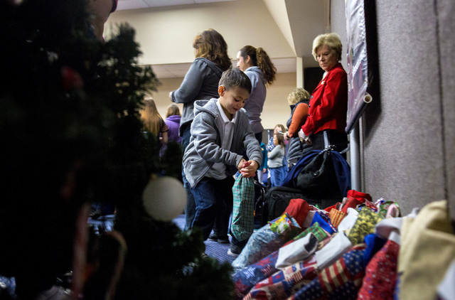 Frederick J. Enrequez Jr., 6, a student from Gordon McCaw Elementary School, places his filled stocking for active troops overseas under the Christmas tree during the 8th annual &quot;Stocking ...