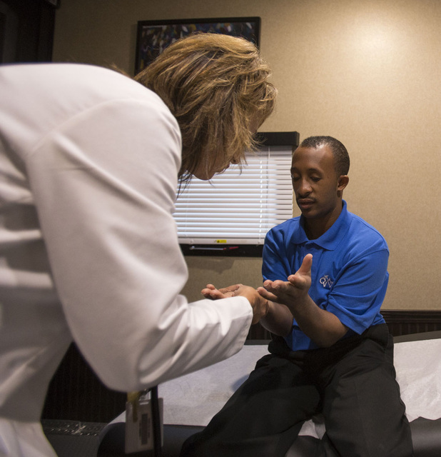 Touro University Nurse Practitioner Sara Dougherty performs a medical exam on Opportunity Village custodian Reginald Daniel, 28, inside Touro's new mobile healthcare clinic in the parking lot of t ...