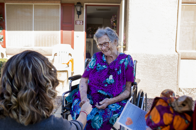 Betty Hurd, center, holds the hand of Maria Aguirre, a St. Thomas More Catholic Community volunteer, while Aguirre delivers Hurd a full Thanksgiving meal to her home, Thursday, Nov. 24, 2016, Hend ...