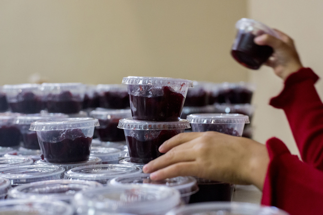 A young volunteer organizes cranberries to be distributed to other volunteers that will deliver full Thanksgiving meals to the homes of senior citizens, Thursday, Nov. 24, 2016, at St. Thomas More ...
