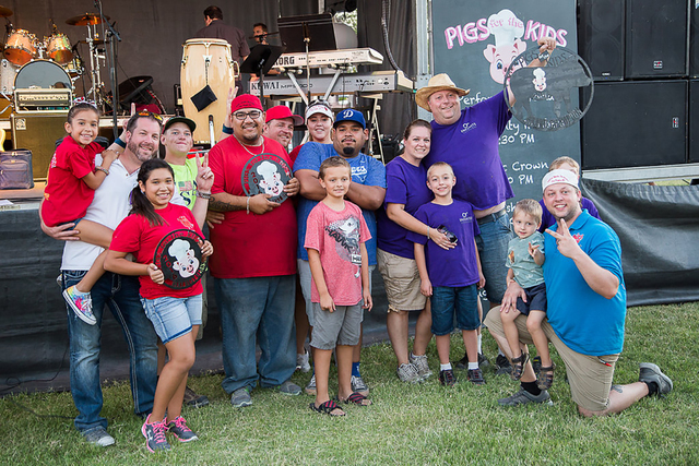 The 2016 Pigs for the Kids' grand champion Team Infinite Smoke BBQ (in purple shirts) and second place team, Rollin Smoke Barbecue, are seen Sept. 17, 2016, at the event held in North Las Vegas.   ...