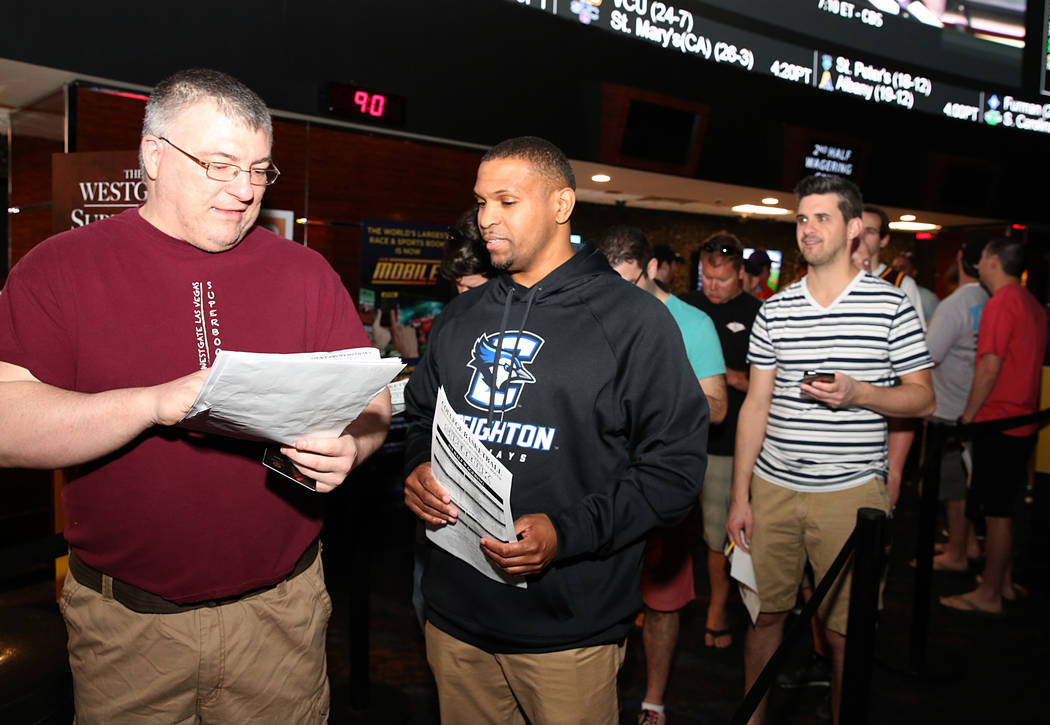Tom Kellehur, left, and Greg Mercer discuss about their bet as they wait in line to bet on the NCAA basketball tournament at Westgate sports book on Thursday, March 16, 2017, in Las Vegas. (Bizuay ...