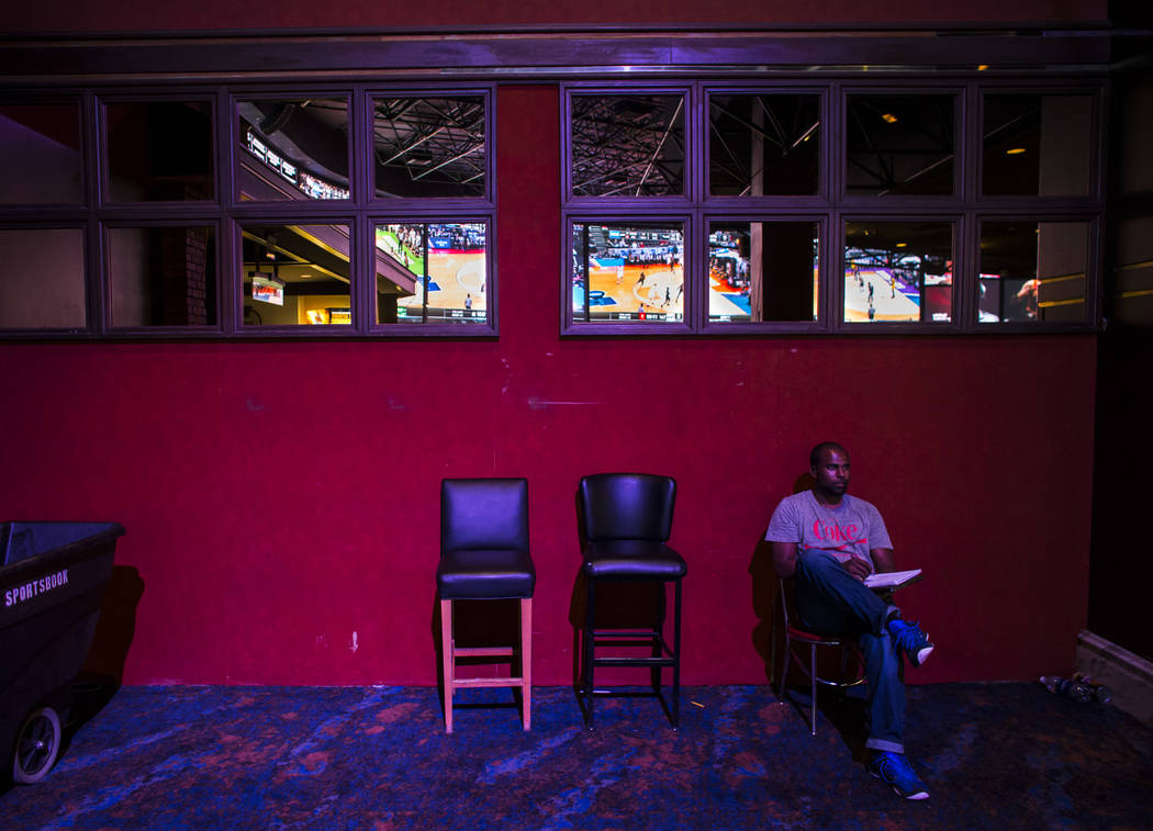 Donald Hodges of Rancho Cucamonga, Calif. watches games, reflected above, during the first day of the NCAA basketball tournament at the Westgate sports book in Las Vegas on Thursday, March 16, 201 ...