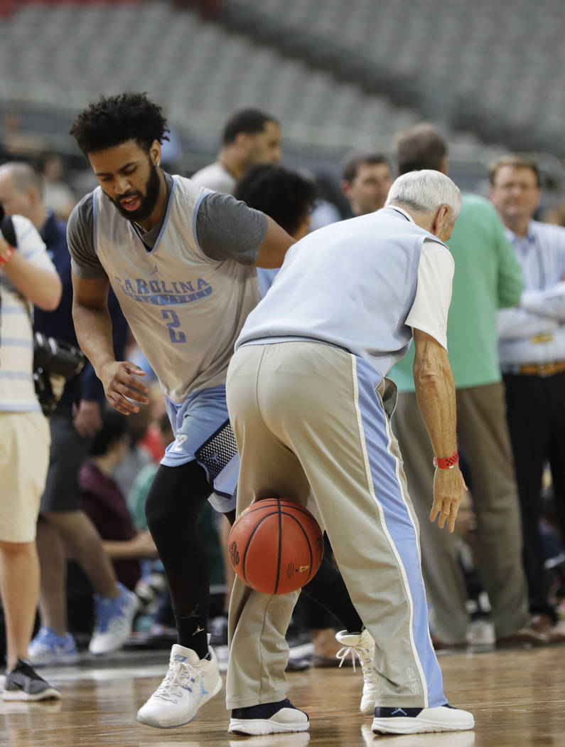 North Carolina's Joel Berry II dribbles past head coach Roy Williams during a practice session for their NCAA Final Four tournament college basketball semifinal game Friday, March 31, 2017, in Gle ...