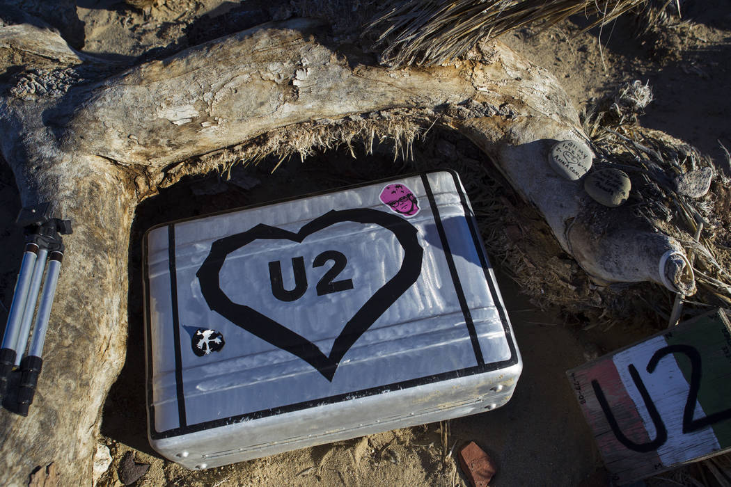 A briefcase with tributes and memorabilia from fans of rock band U2 sits with the fallen tree t ...