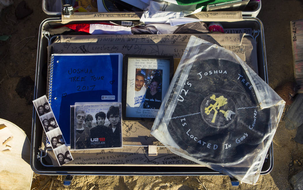A briefcase with tributes and memorabilia from fans of rock band U2 sits with the fallen tree t ...