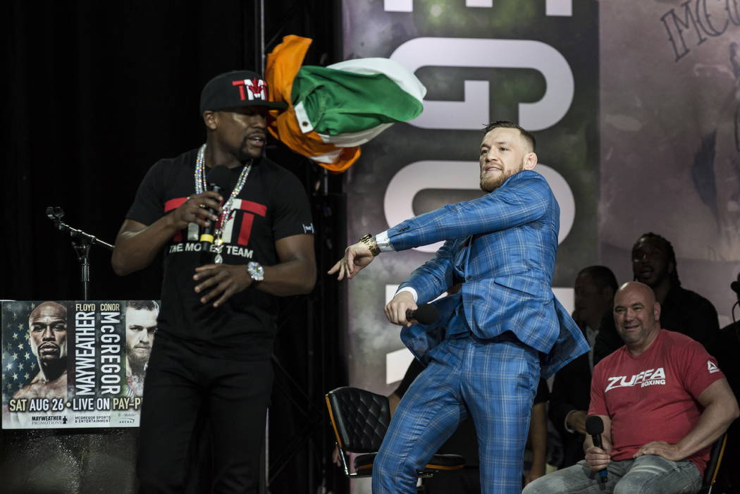 Conor McGregor, right, throws an Irish flag at Floyd Mayweather during a promotional stop in Toronto on Wednesday, July 12, 2017, for their upcoming boxing match in Las Vegas. (Christopher Katsaro ...