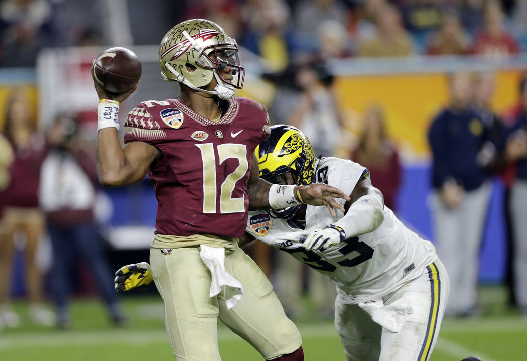 Florida State quarterback Deondre Francois (12) looks to pass under pressure from Michigan defensive end Taco Charlton (33), during the second half of the Orange Bowl NCAA college football game, F ...