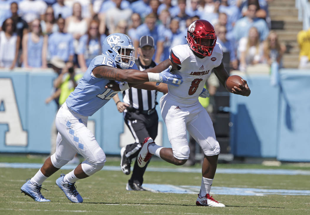 Louisville quarterback Lamar Jackson (8) runs the ball as North Carolina's Tomon Fox (12) chases during the first half of an NCAA college football game in Chapel Hill, N.C., Saturday, Sept. 9, 201 ...