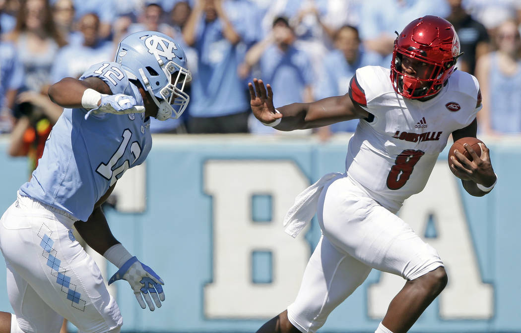 FILE - In this Sept. 9, 2017, file photo, Louisville quarterback Lamar Jackson (8) runs the ball as North Carolina's Tomon Fox (12) chases him during the first half of an NCAA college football gam ...