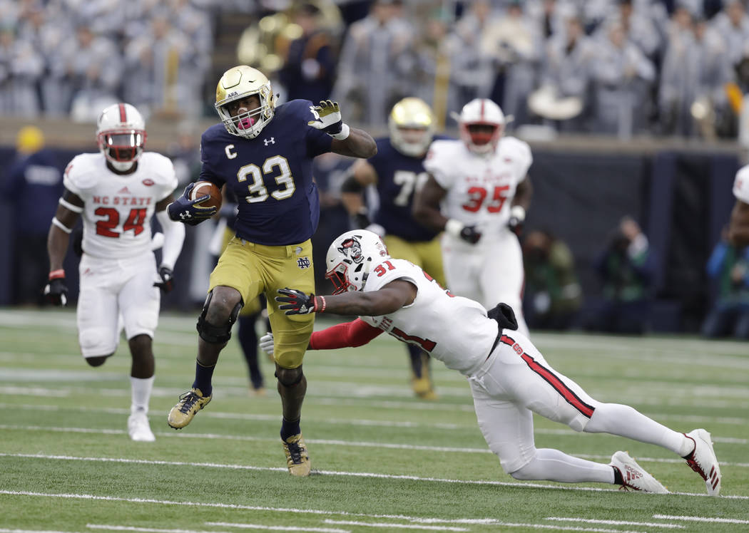 Notre Dame running back Josh Adams is tackled by North Carolina State safety Jarius Morehead (31) during the first half of an NCAA college football game, Saturday, Oct. 28, 2017, in South Bend, In ...