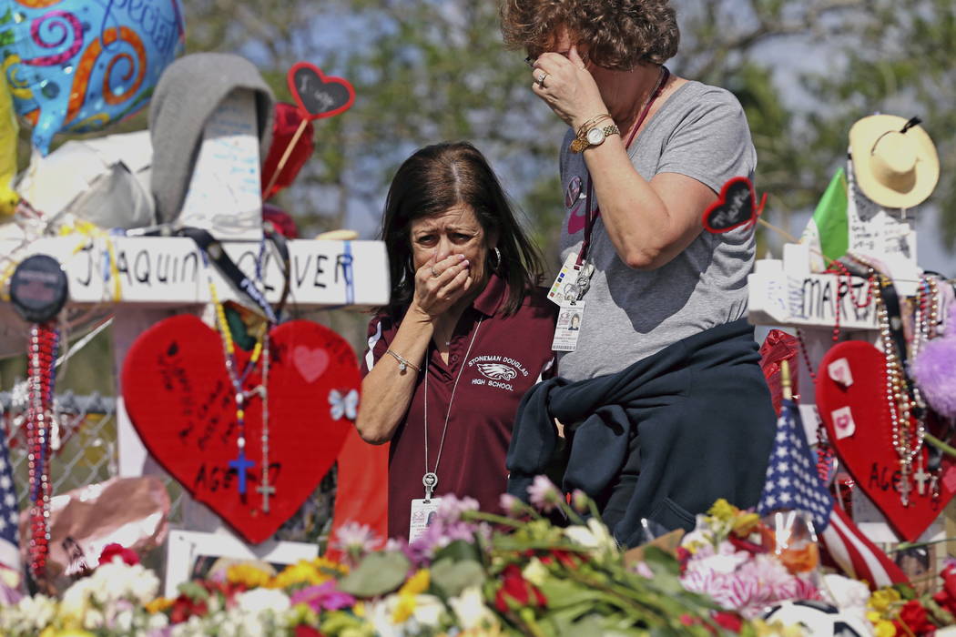 Marjory Stoneman Douglas High School administrative employees Margarita LaSalle, left, and JoEllen Berman, walk along the hill near the school lined with 17 crosses to honor the students and teach ...