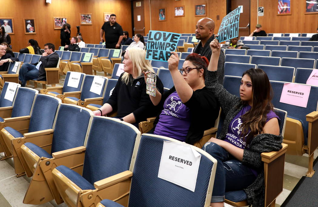 Laura Hernandez, center, and Kristina Hernandez, right, hold their signs up high after the majority of the crowd left following the Clark County School Board's decision to pull a controversial gen ...