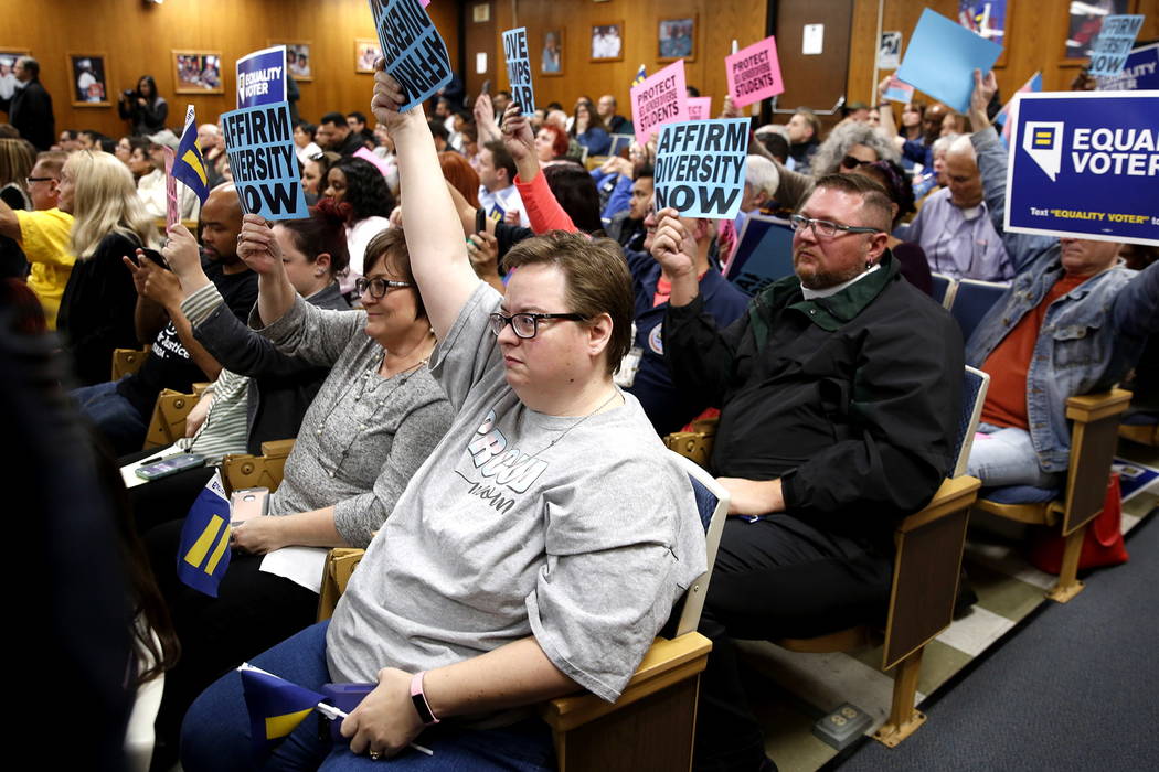 Attendees hold up signs during a Clark County School Board meeting, which ended with the board pulling a controversial gender-diverse policy from the agenda, at the Edward Greer building on Flamin ...