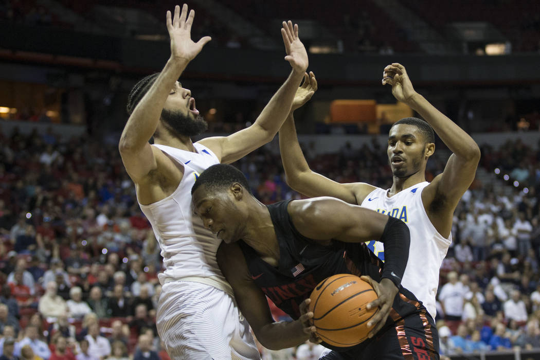 UNLV Rebels forward Brandon McCoy (44) is pressured by Nevada Wolf Pack forward Caleb Martin (10) and guard Josh Hall (33) in the second half of the Mountain West Conference men's basketball tourn ...