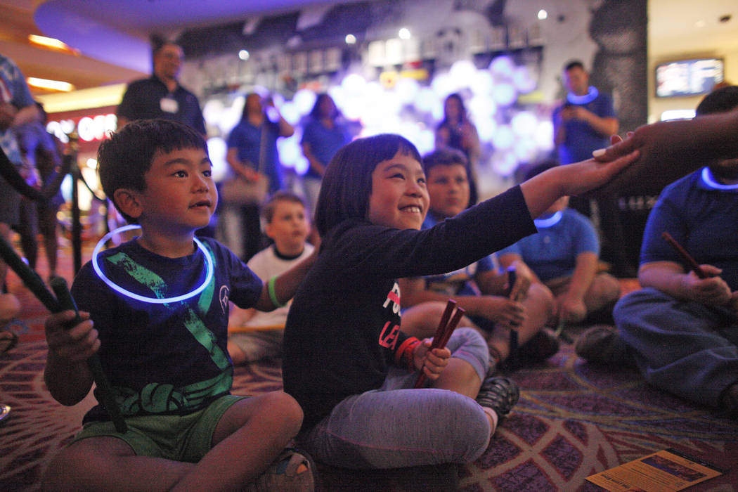 Analu Tam, 6, left, watches as his sister Kailana Tam, 9, grabs the hand of teacher Linda Austin during a drum circle activity at the Luxor hotel-casino in Las Vegas, Sunday, June 10, 2018. The ev ...
