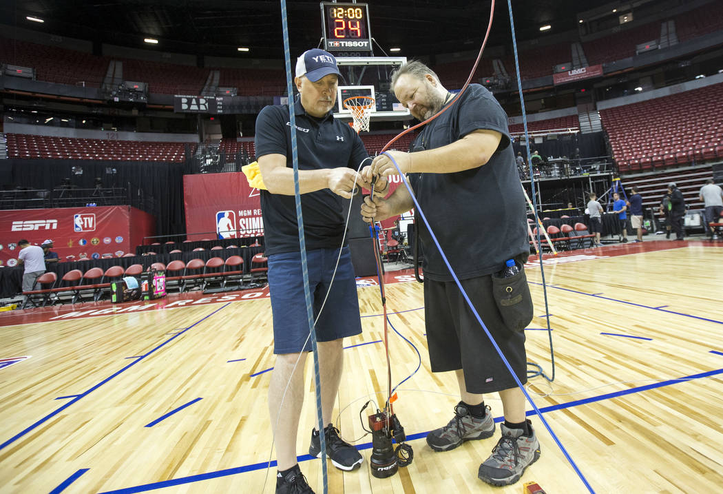 C360 camera operator Joe Tomko, left, and cable rigger Munch Kromer install an over-head camera used to validate 3-point baskets during games ahead of the 2018 NBA Summer League basketball tournam ...