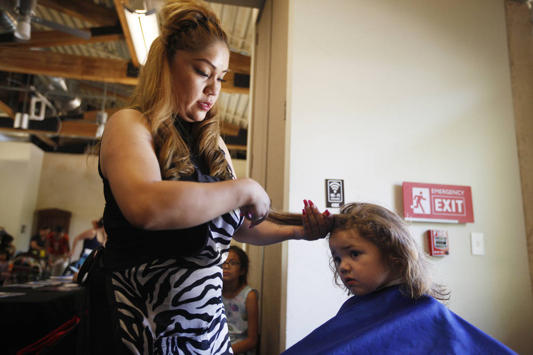 Diana Jimenz cuts the hair of Abbey Dallman, 3, at the annual Back to School Fair organized by the Happy Face Foundation at Springs Preserve in Las Vegas, Sunday, Aug. 5, 2018. Students received f ...