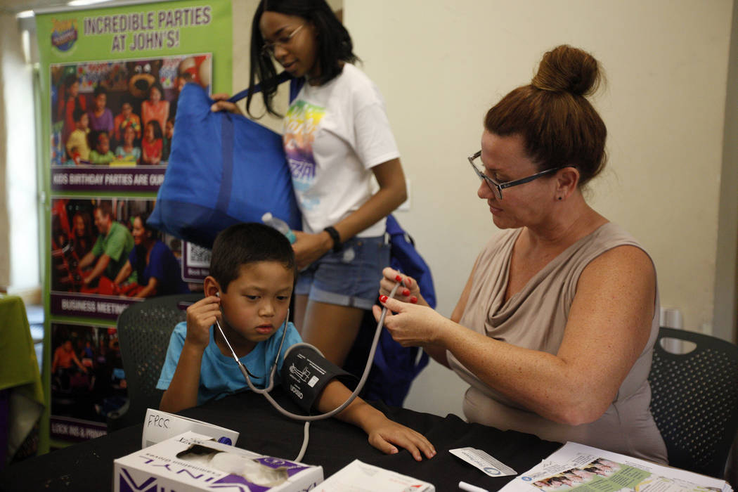 Dr. Ivonne Draughon lets Maddox Sourivong, 6, listen to his heartbeat after he received a free blood pressure reading at the annual Back to School Fair organized by the Happy Face Foundation at Sp ...