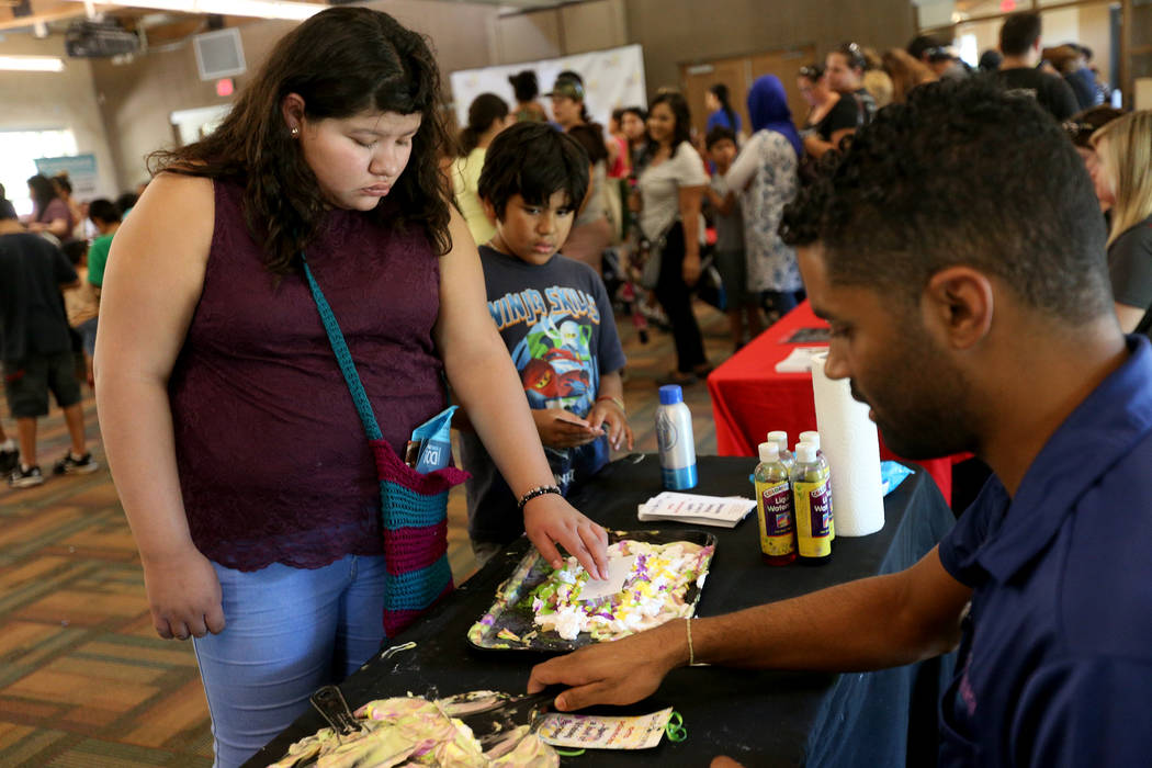 Madeline Guzman, 14, decorates a bookmark at the Children's Museum booth at the annual Back to School Fair organized by the Happy Face Foundation at Springs Preserve in Las Vegas, Sunday, Aug. 5, ...