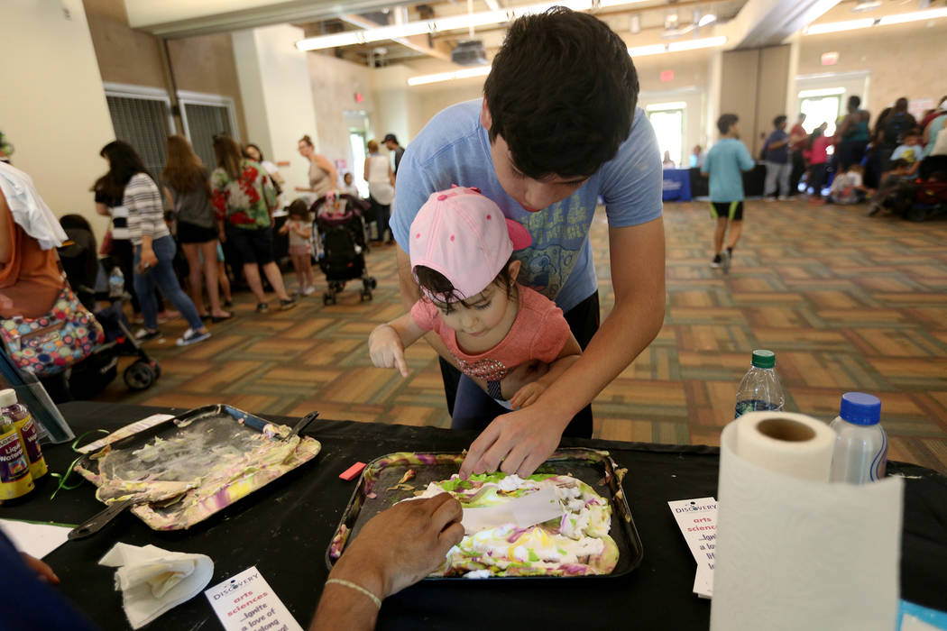 Javier Barra, 18, holds his niece Mia Taliercio, 2, as they decorate a bookmark at the Children's Museum booth at the annual Back to School Fair organized by the Happy Face Foundation at Springs P ...