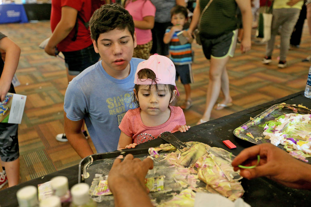 Javier Barra, 18, holds his niece Mia Taliercio, 2, as they decorate a bookmark at the Children's Museum booth at the annual Back to School Fair organized by the Happy Face Foundation at Springs P ...