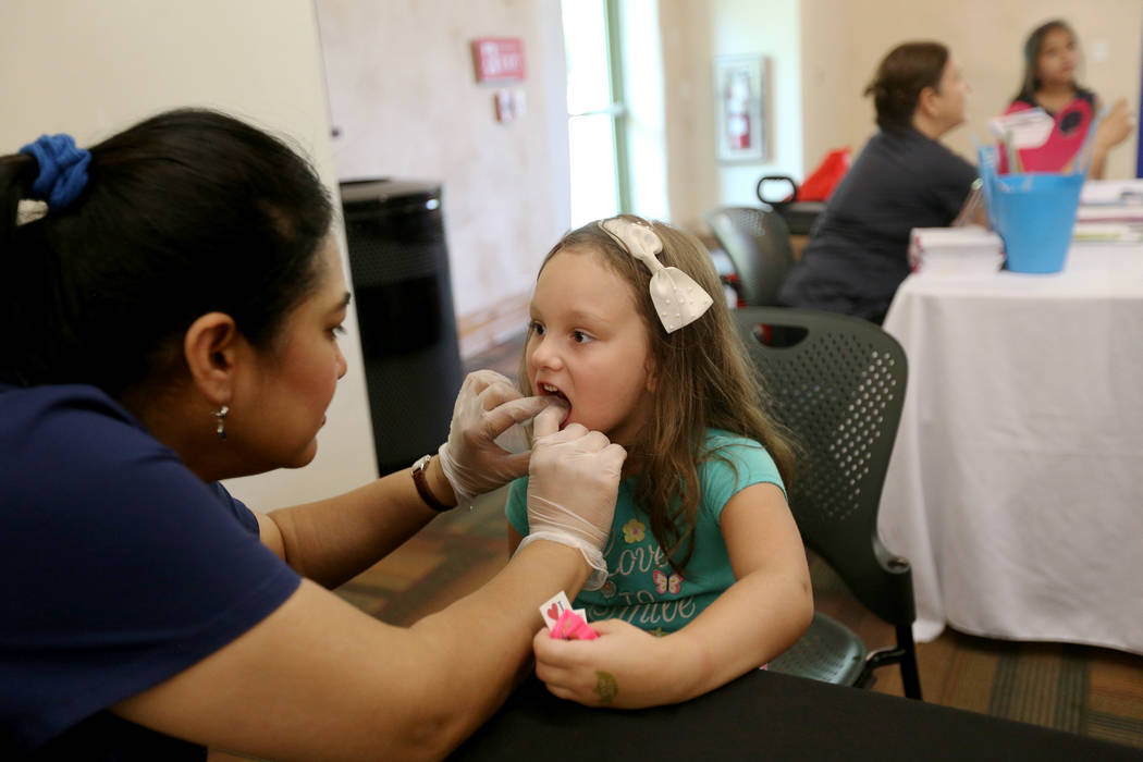 Dr. Lubna Anwar examines the teeth of Maria Paula Hahn, 5, at the annual Back to School Fair organized by the Happy Face Foundation at Springs Preserve in Las Vegas, Sunday, Aug. 5, 2018. Students ...
