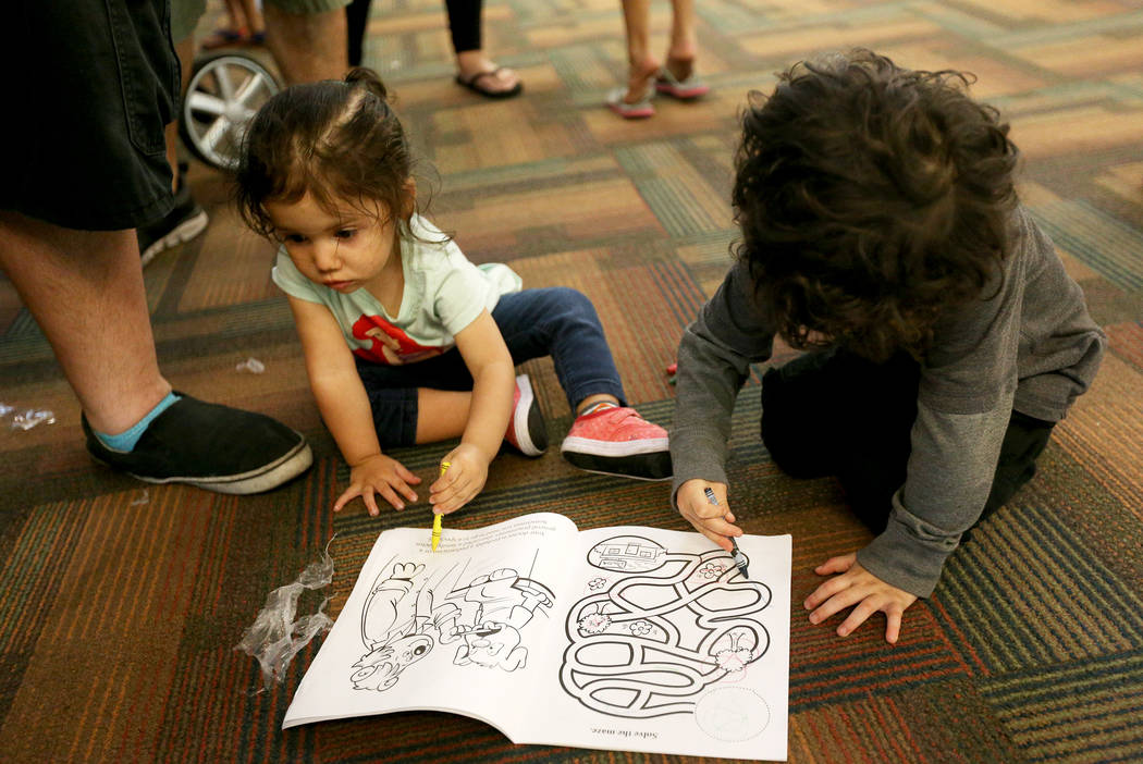 Ariel Gonzales, 1, left, and her brother Nathan Gonzales, 3, colors a coloring book they received at the annual Back to School Fair organized by the Happy Face Foundation at Springs Preserve in La ...