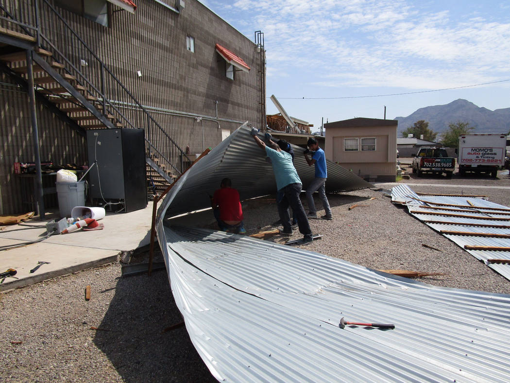 Workers try to dismantle a sheet metal awning that collapsed in Saturday night’s storm behind a business in east Las Vegas near Lake Mead Boulevard and Nellis Boulevard on Sunday, August 12, 201 ...