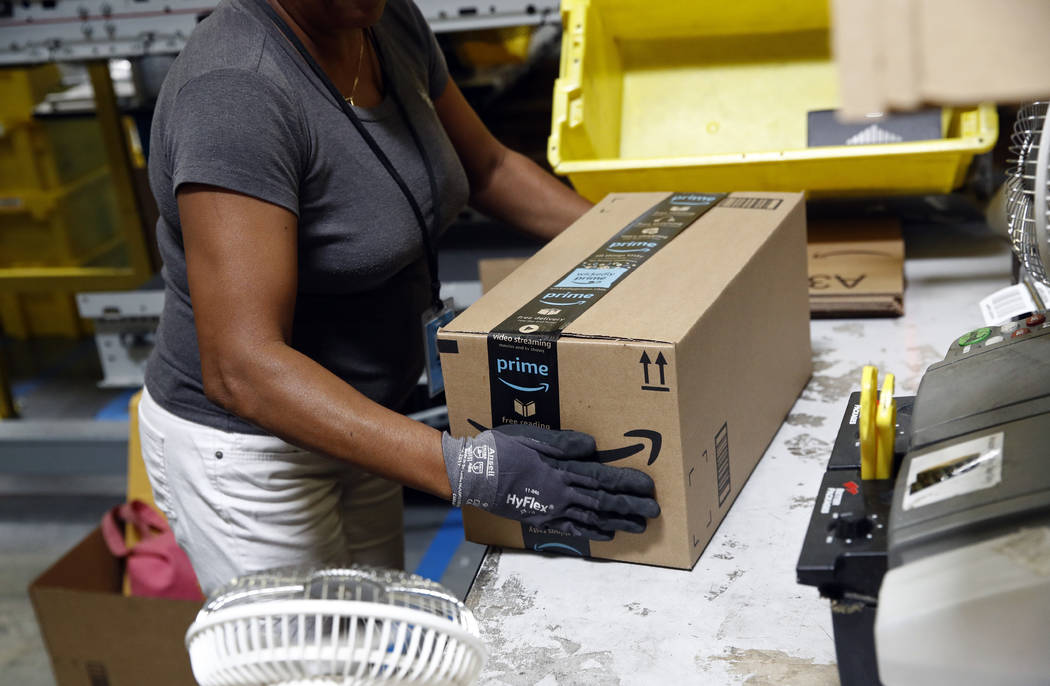 Myrtice Harris applies tape to a package before shipment at an Amazon fulfillment center in Bal ...