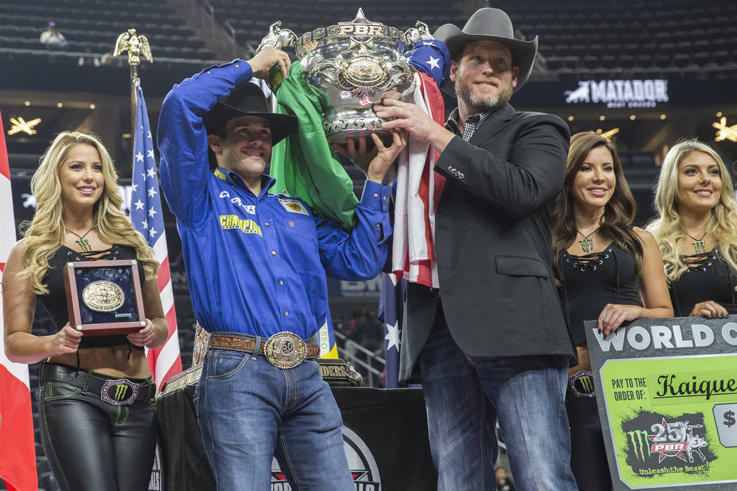 Kaique Pacheco, left, and PBR CEO Sean Gleason hold up Pacheco's trophy after the Brazilian won the Professional Bull Riders World Championship on Sunday, November 11, 2018, at T-Mobile Arena, in ...