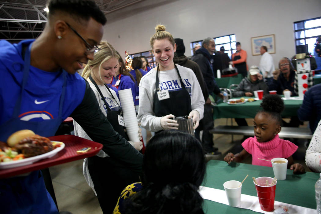 Donovan Smith, 17, from left, Hallie Borgel, 17, and Tatum Rowand, 17, talk to guest Laurice Adams at the Christmas meal sponsored by the Frank and Victoria Fertitta Foundation, at Catholic Charit ...