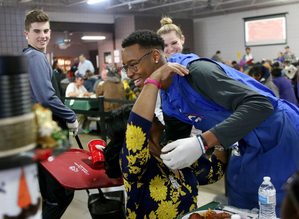 Volunteer Donovan Smith, 17, a Bishop Gorman football team member, hugs Laurice Adams, a guest, at the Christmas meal sponsored by the Frank and Victoria Fertitta Foundation, at Catholic Charities ...