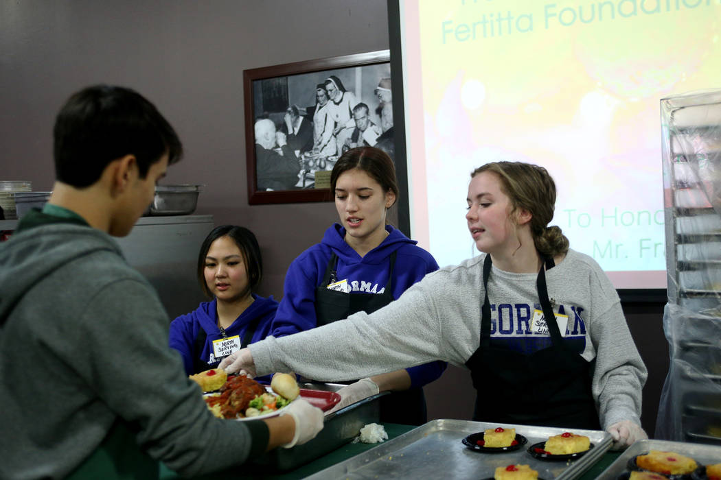 Kelly Hashiro, 17, from left, Keira Fincher, 15, and Haley Taylor, 17, serve dessert and bread at the Christmas meal sponsored by the Frank and Victoria Fertitta Foundation, at Catholic Charities ...