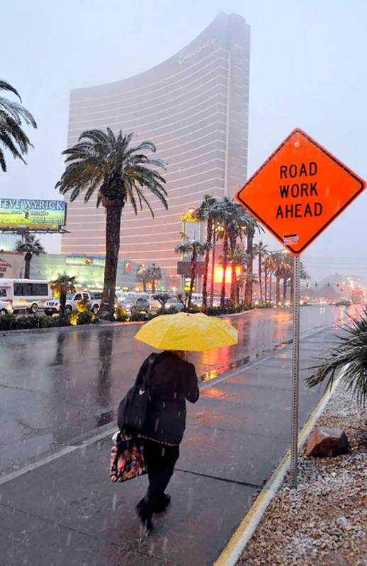 A woman braves the elements as she walks down the Las Vegas Strip near the Encore on Dec. 17, 2 ...