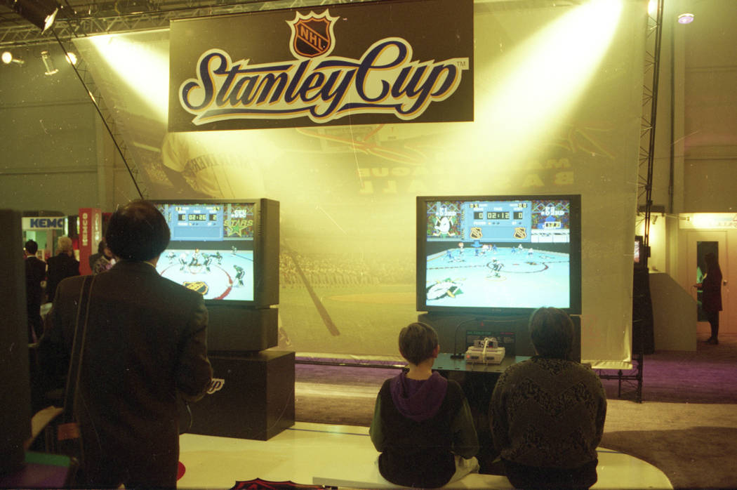 Two people play the NHL Stanley Cup game on the Super Nintendo gaming system on a big screen television at the 1993 Consumer Electronics Show at the Las Vegas Convention Center.