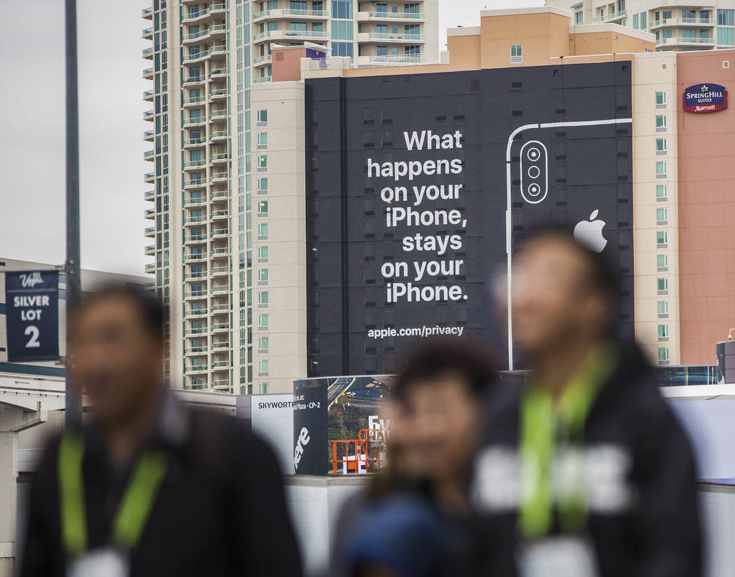 Visitors walk past an Apple advertisement on the south side of SpringHill Suites that is easily visible from the CES 2019 tech show at the Las Vegas Convention Center on Monday, Jan. 7, 2019, in L ...
